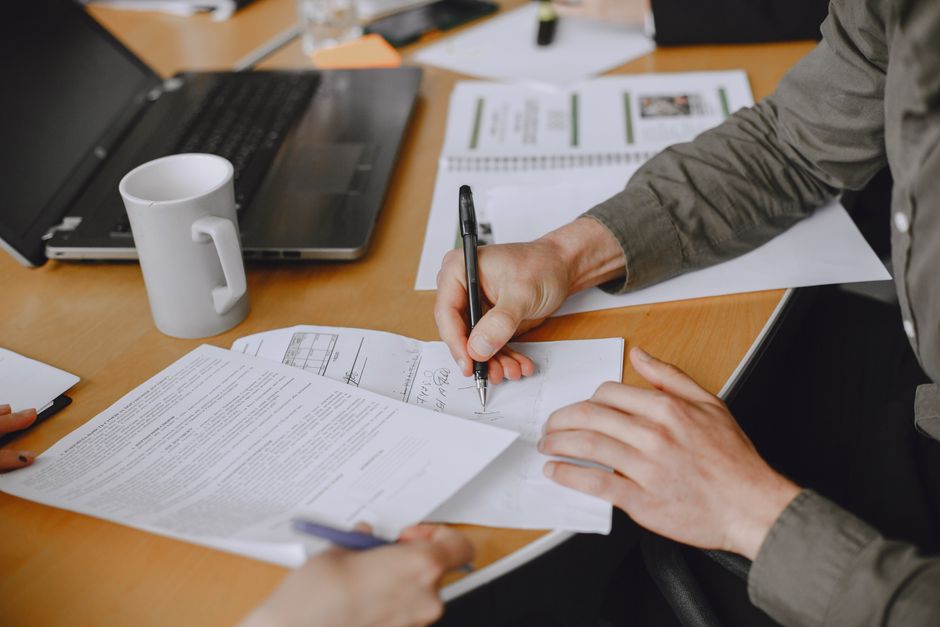 Ausgefülltes Muster einer Auftragsbestätigung wird gegengezeichnet — Unterschrift am Besprechungstisch