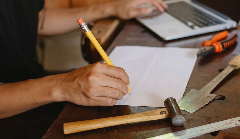 Auftragsbestätigung Vorlage im Handwerksbetrieb ausfüllen — Notizen und Laptop an der Werkbank
