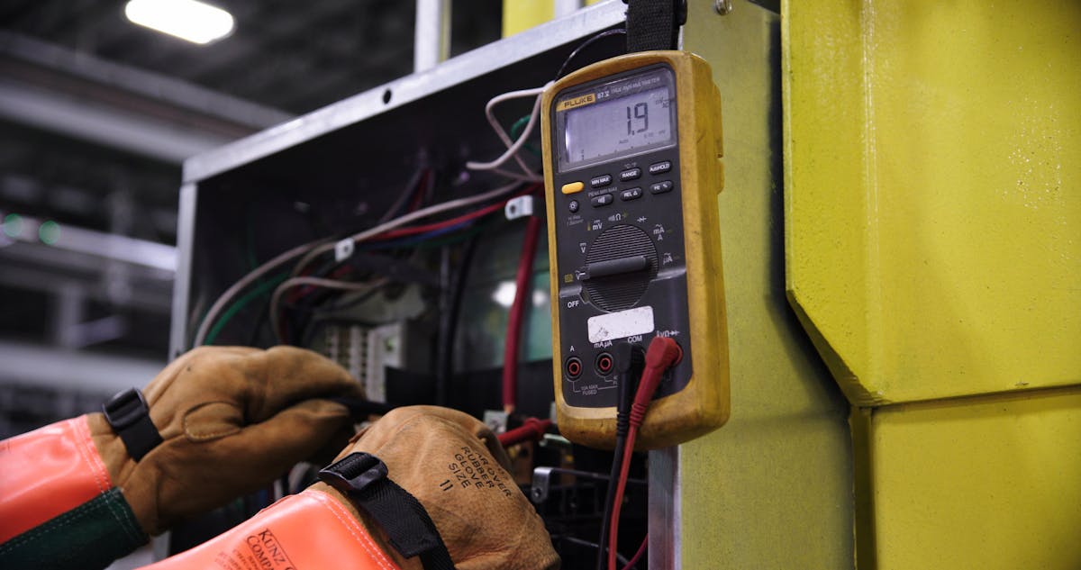 Elektriker prüft Schaltschrank mit Multimeter bei der Eigenabnahme